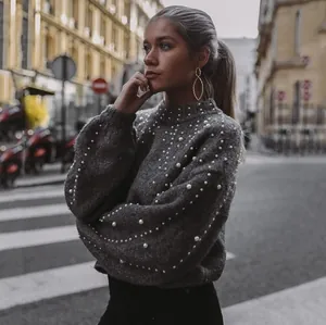 Elegant grey knit sweater with white pearl embellishments shown on a model outdoors