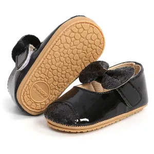 Close-up detail of black patent leather baby shoes with glitter bow and non-slip sole