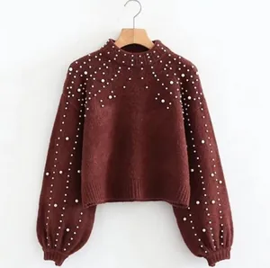 Detailed view of women's burgundy knit pullover sweater with white pearl embellishments