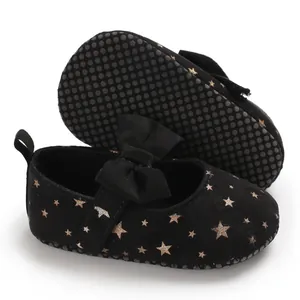 Nahaufnahme schwarzer Baby-Prinzessinenschuhe mit goldenen Sternen und süßer Schleife.