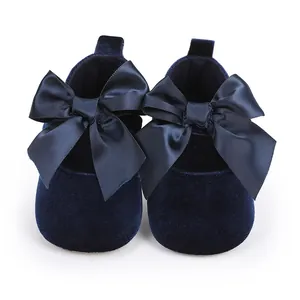 Detail van marineblauwe fluwelen baby prinsessenschoenen met grote satijnen strikken.