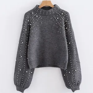 Close-up detail of grey knitted sweater featuring elegant white pearl bead accents