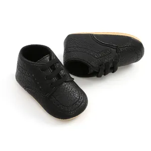 Close-up detail of black PU leather baby shoes with brogue patterns and soft soles
