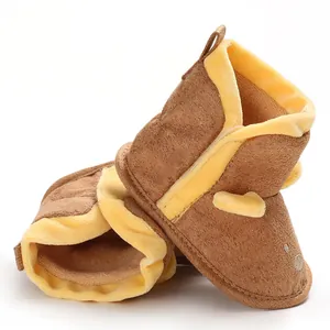 Gros plan de bottines en peluche marron et jaune pour bébé avec semelle souple pour l'hiver