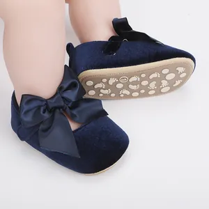 Detailopname van marineblauwe fluwelen baby prinsessenschoenen met satijnen strikjes.