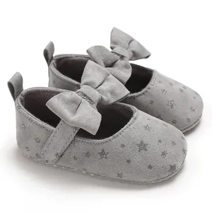 Detailansicht grauer Baby-Prinzessinenschuhe mit Glitzersternen und großer Zierschleife.