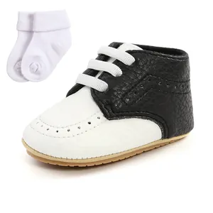 Detailed view of black and white wingtip baby shoes with soft soles and white socks