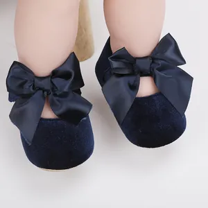 Detailopname van donkerblauwe fluwelen babyschoentjes met grote satijnen strikken