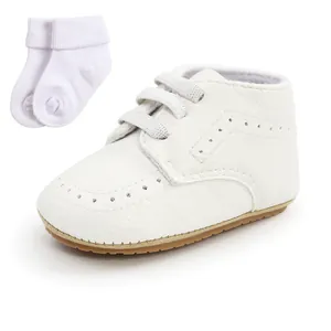 Macro view of white soft-sole baby pre-walker shoes and matching white cotton socks