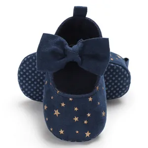 Nahaufnahme blauer Baby-Lauflernschuhe mit großer Schleife und goldenen Glitzersternen
