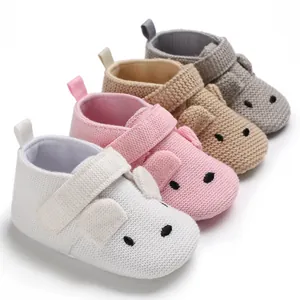 Detailansicht weicher gestrickter Babyschuhe in Weiß, Rosa, Beige und Grau für erste Schritte