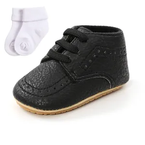 Detail view of black textured infant walking shoe with a pair of white cotton socks