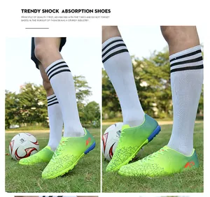 Close-up view of lime green youth turf soccer shoes with anti-slip design on grass.