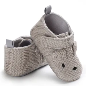 Nahaufnahme von grauen gestrickten Babyschuhen mit weicher Sohle und Tiergesicht