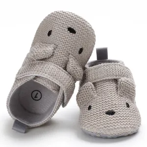 Detailansicht grauer gestrickter Babyschuhe mit niedlichem Tiergesicht für erste Schritte
