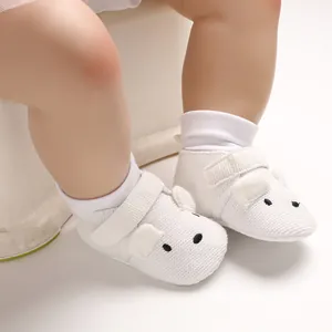 Nahaufnahme weißer gestrickter Babyschuhe mit süßem Tiergesicht und weicher Sohle