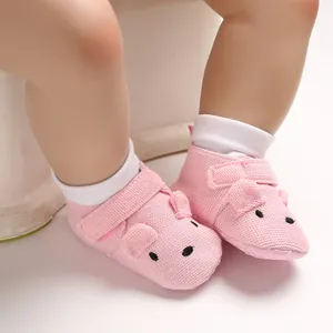 Detaillierte Makroansicht rosa gestrickter Babyschuhe mit Tiergesicht und weicher Sohle für Babys.