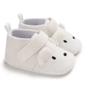 Detailaufnahme von weißen gestrickten Babyschuhen mit süßem Tiergesicht und weicher Sohle