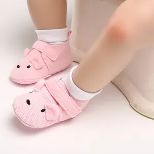 Nahaufnahme rosa Strick-Babyschuhe mit süßem Schweinedesign und weicher Sohle