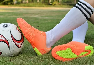 Detailed macro view of orange adolescent soccer shoes with TF studs on artificial grass