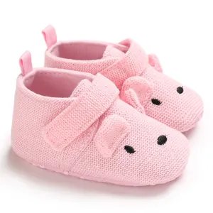 Detailansicht von rosa gestrickten Baby-Lauflernschuhen mit süßem Schweinedesign und weicher Sohle