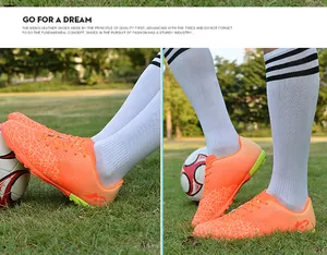 Close-up of vibrant orange youth soccer turf cleats on a green grass field