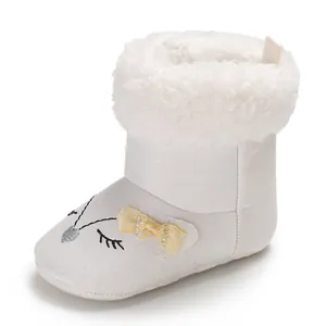 Gros plan sur des bottes d'hiver blanches pour bébé avec broderie et bordure en fourrure