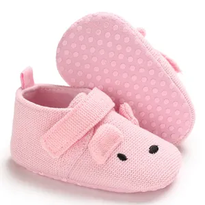 Nahaufnahme von rosa gestrickten Babyschuhen mit süßem Schweinedesign und weichen Sohlen