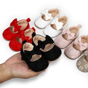 Mano sosteniendo un zapato de princesa de encaje negro para bebé entre varios colores