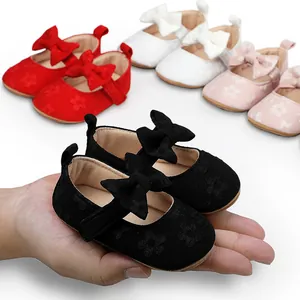 Detalle de zapatos de princesa para bebé de encaje negro con lazo en la mano