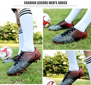 Durable youth soccer cleats with red-black gradient design on outdoor grass field