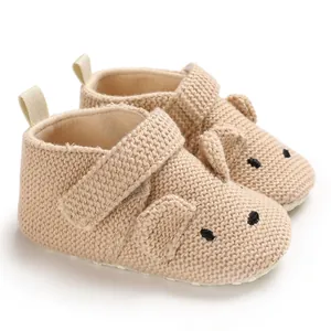 Nahaufnahme der weichen beigen gestrickten Babyschuhe mit niedlichem Tiergesicht
