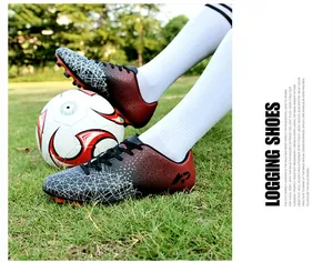 Youth soccer shoes with red and black gradient and white patterns on artificial grass
