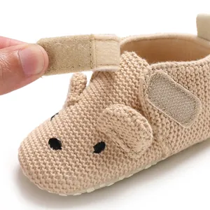 Detailaufnahme eines beigen Strick-Babyschuhs mit Klettverschluss und Tiergesicht-Design