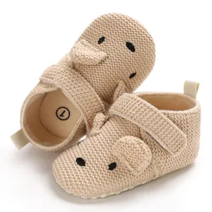 Nahaufnahme von beigen gestrickten Lauflernschuhen für Babys mit süßem Tiergesicht