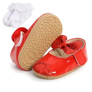 Detail view of red sequin bow baby shoes with textured non-slip sole and white socks