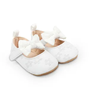 Detalle de zapatos de princesa para bebé en encaje blanco con lazo grande y bordado floral