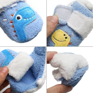 Detail van zachte blauwe pluche baby winterschoentjes met dinosaurus borduursel.