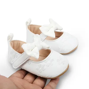 Detalle de zapatos de princesa para bebé niña en encaje blanco con lazo y cierre de velcro