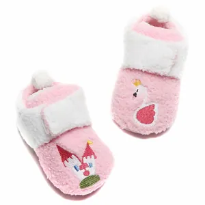 Detail van roze pluchen baby winterlaarsjes met borduursel van een zwaan en kasteel.