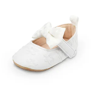Detalle de los zapatos de encaje blanco para bebé niña con un lazo grande elegante