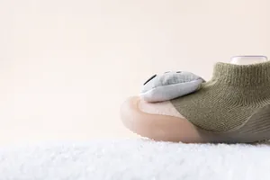 Nahaufnahme grüner Baby-Socken-Schuh mit weicher Anti-Rutsch-Sohle und süßem Detail.