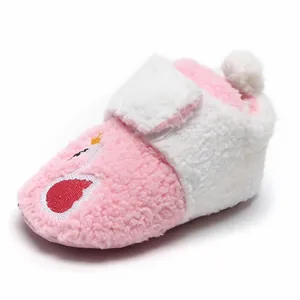 Detailopname van roze en witte fleece babyschoentjes met zwaanborduurwerk en pompon-detail