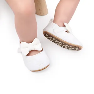 Detalle de zapatos de princesa elegantes de encaje blanco para bebé con un gran lazo