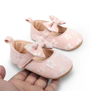 Detalle de los zapatos de princesa para bebé de encaje rosa con lazo decorativo