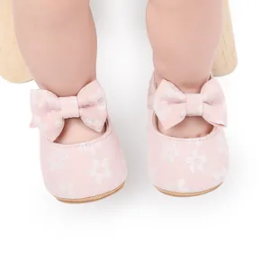 Primer plano de zapatos de princesa rosas para bebé con estampado floral y un lazo