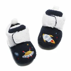 Detailweergave van pluchen baby winterschoenen met raket- en UFO-ruimteborduurwerk.