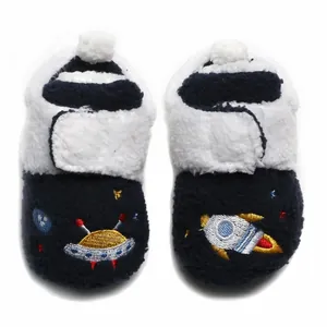 Detailopname van winterse baby-pluche schoentjes met raket- en ufo-borduurwerk motief.