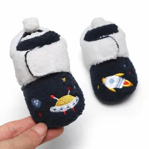 Detailweergave van marineblauwe pluche babyschoenen met geborduurde UFO en raket