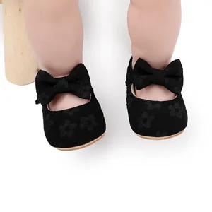 Primer plano de elegantes zapatos de princesa para bebé negros con encaje floral y lazo.